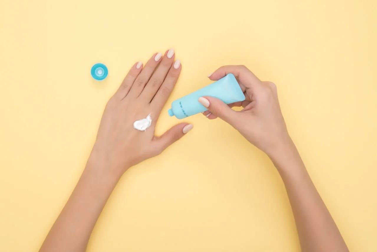 woman applying moisturizer on the back of her hand