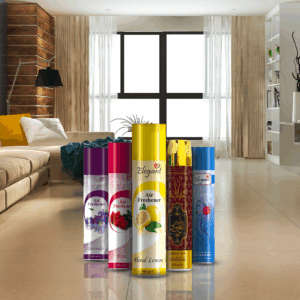 Five colorful air freshener spray cans displayed in the foreground of a modern living room. The cans feature different scents, including lavender, rose, floral lemon, oud, and a blue variant labeled “Elegant Lady,” standing upright on a glossy floor with a bright, stylish interior in the background.